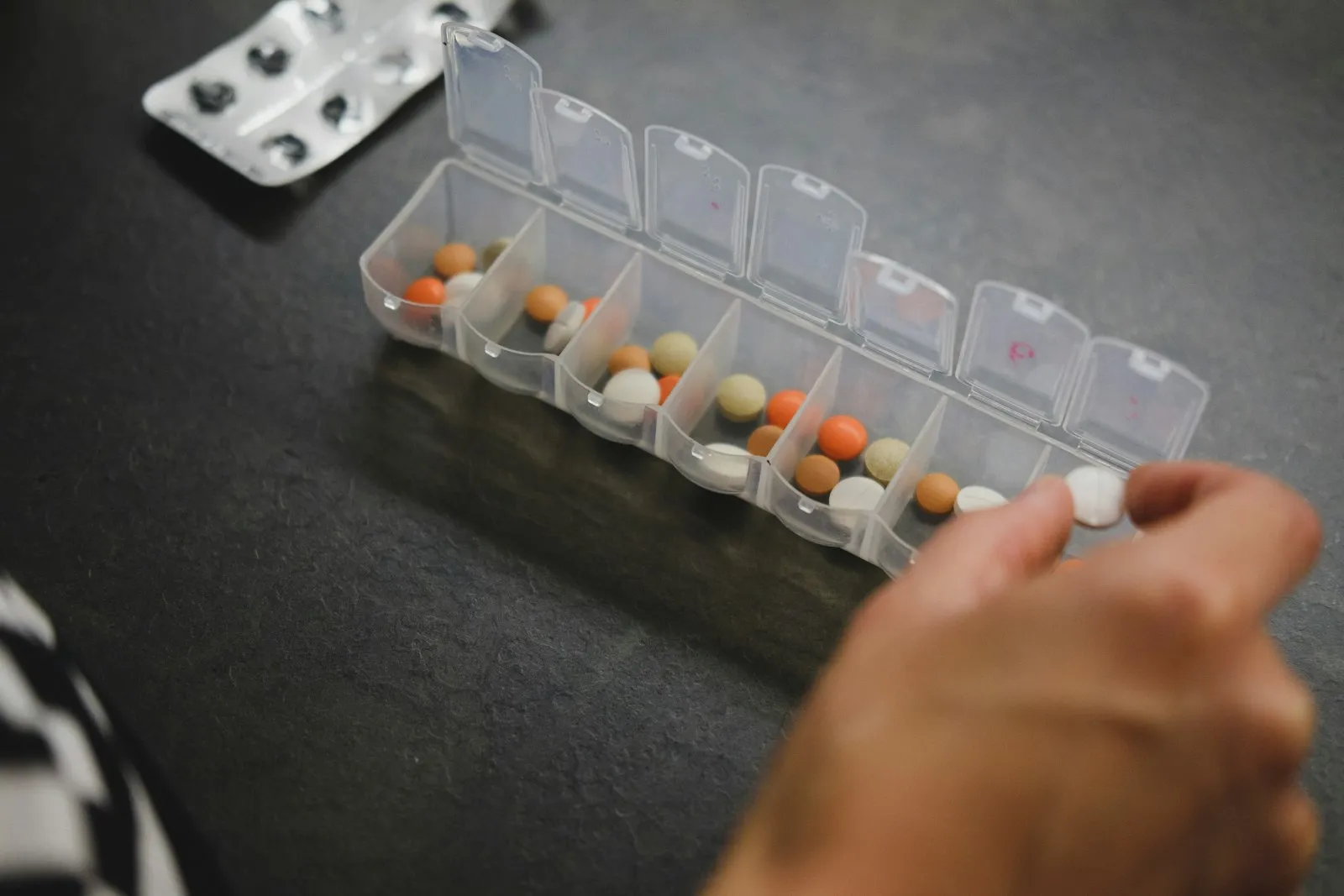 A hand holding a small pill organizer box
